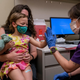 A 3-year-old sits on the lap of her mother and gets a high five from a nurse after receiving her first dose of the Pfizer covid-19 vaccination at UW Medical Center on June 21, 2022 in Seattle, Washington.